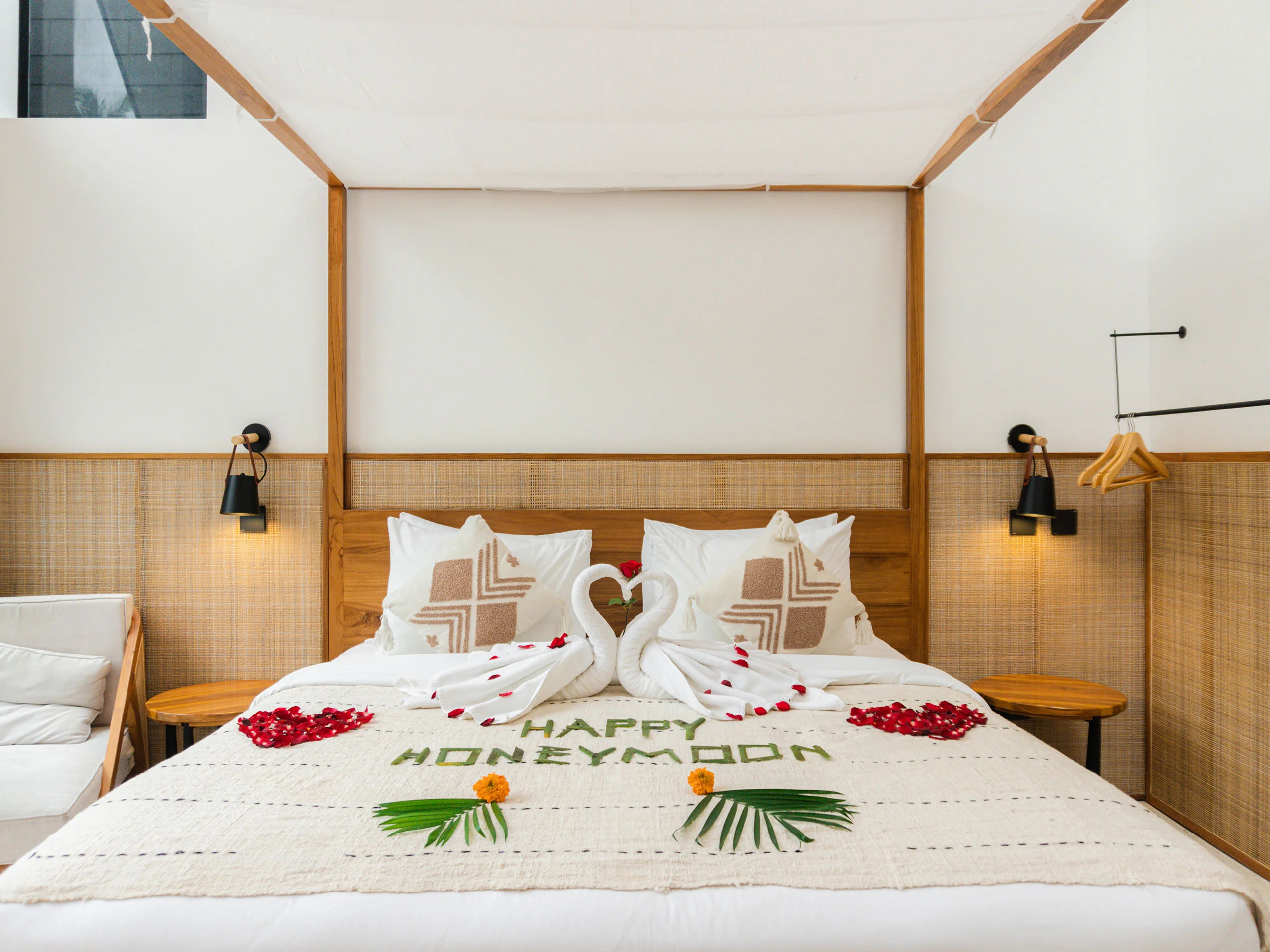 Honeymoon bed setup with swan towels, rose petals, and tropical leaves at Tannari Villas