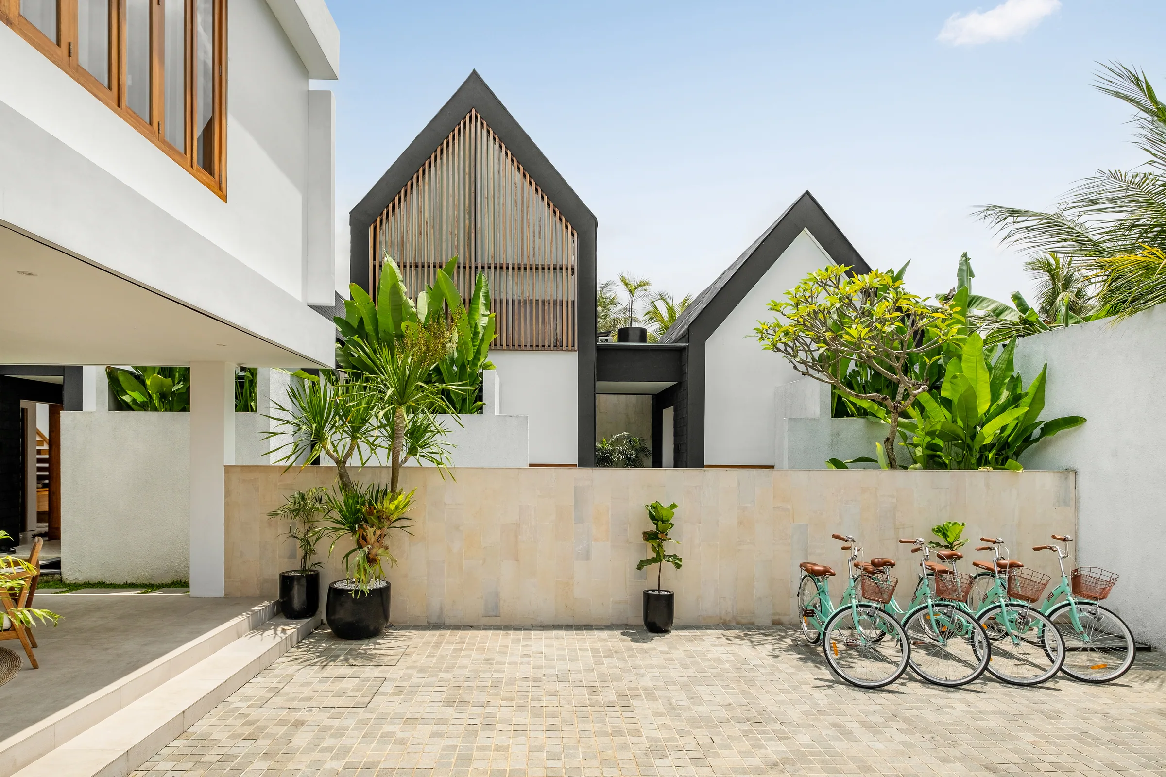 Tannari Villas arrival courtyard with both villas, tropical planting, and guest bicycles